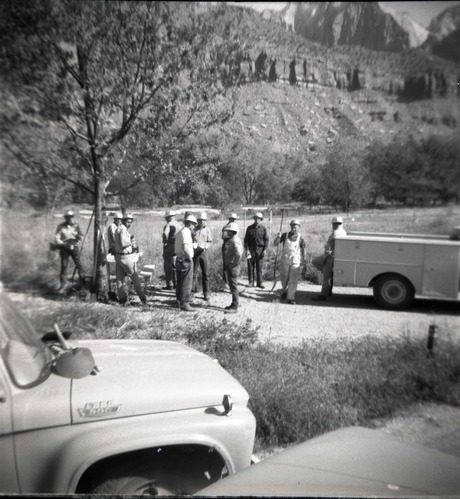 Maintenance crew with shovels on break in A-Loop (Watchman) Campground, trucks parked nearby.