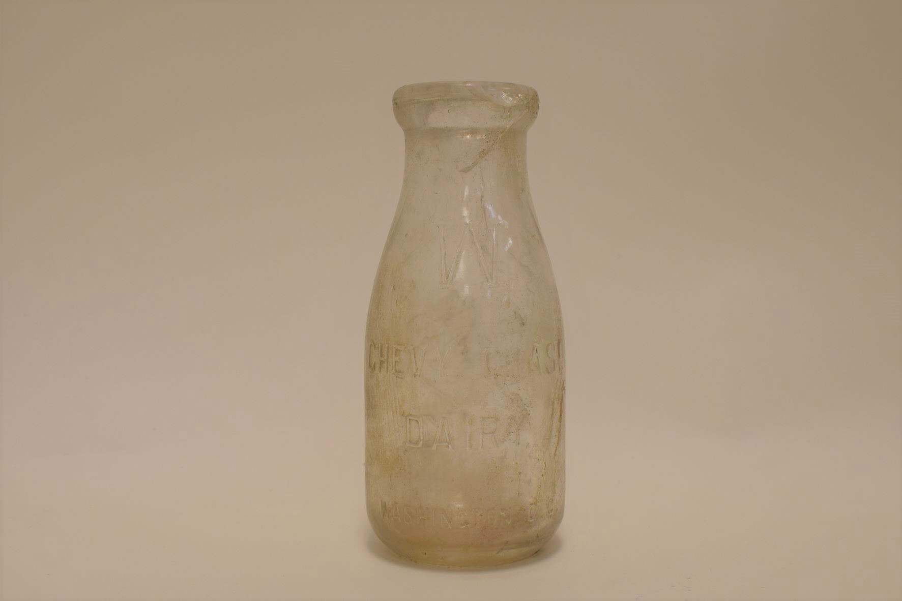 Clear, glass milk bottle.

Transcription:
“W
Chevy Chase Dairy
Washington, D.C.”
