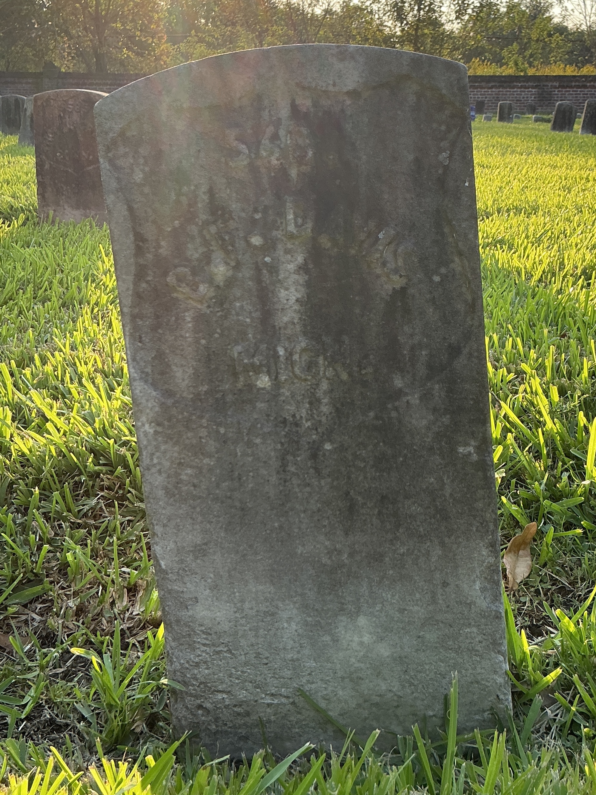 Front of historic upright marble headstone with recessed shield face.