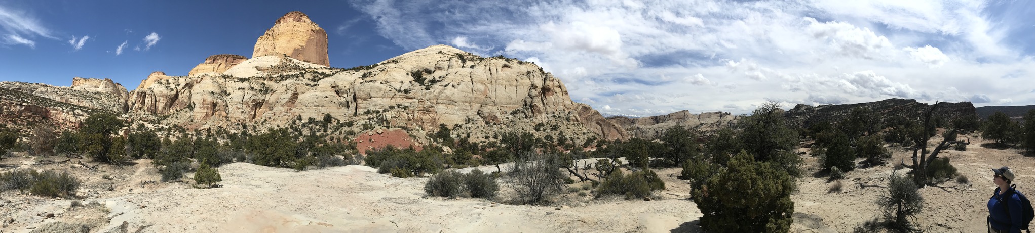 A large, tall sandstone spire to the left of the frame, panning right is a level sandstone area with a person at far right.