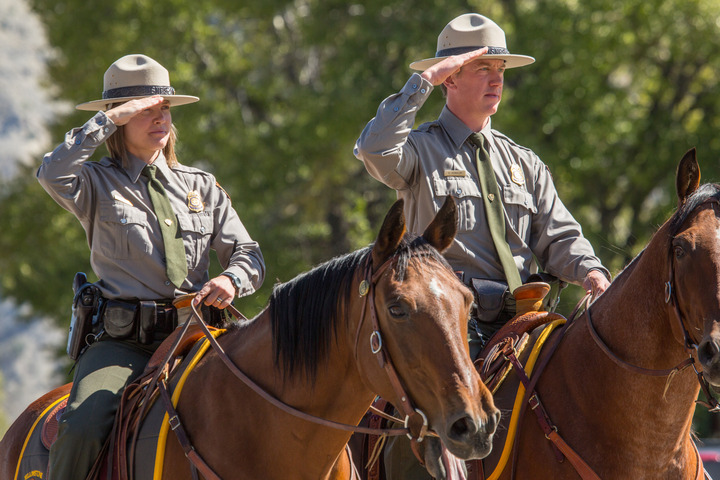 Two rangers on horseback salute the flag