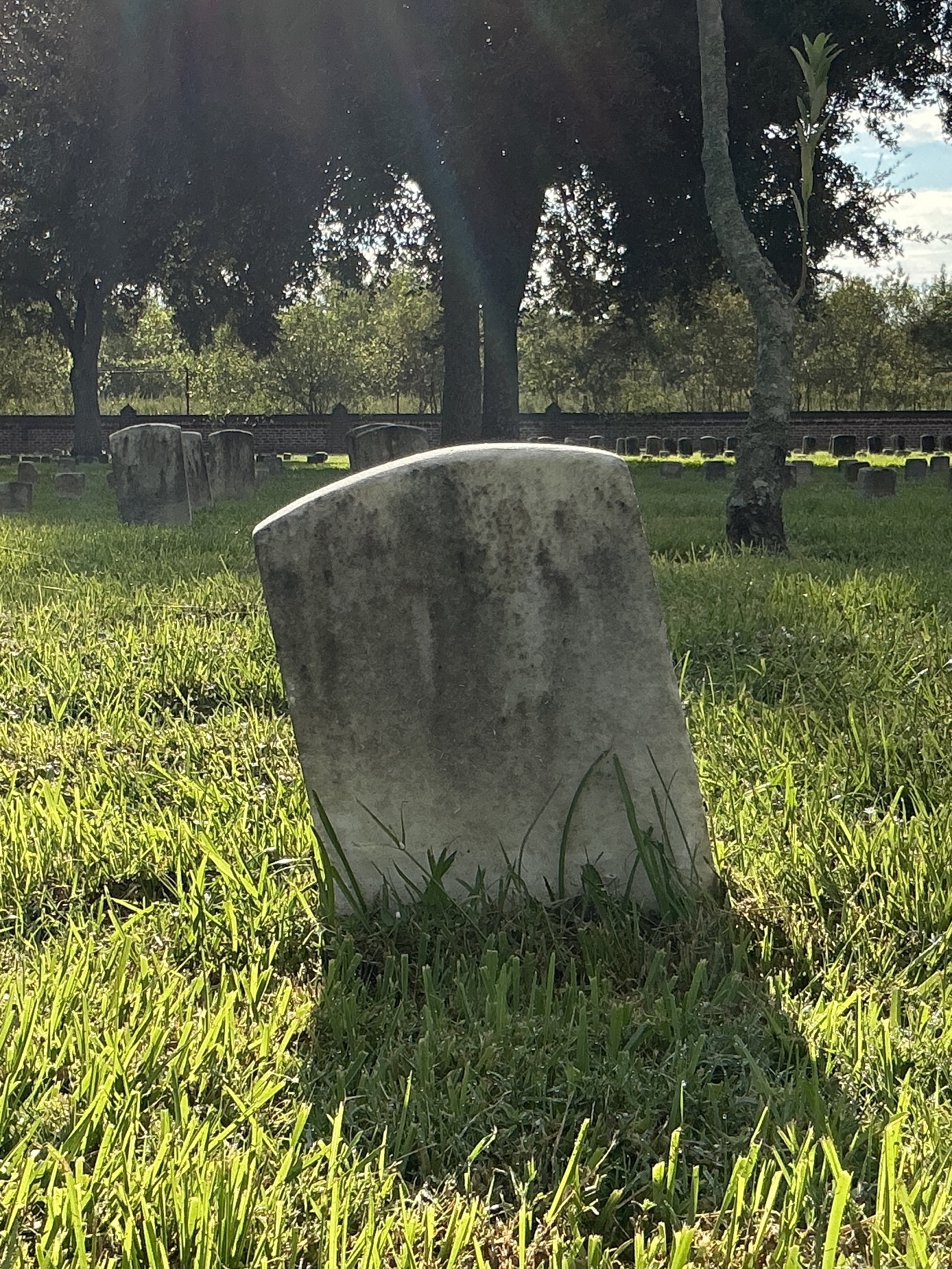 Back of historic upright marble headstone with recessed shield face.