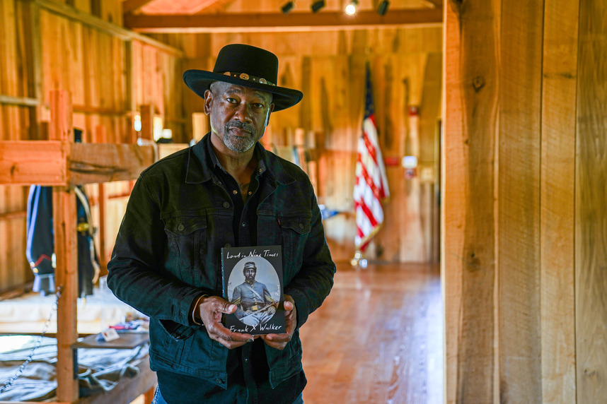 Two-time Kentucky Poet Laureate, Frank X. Walker, holds his book as he is photographed in a reconstructed Civil War barracks. 