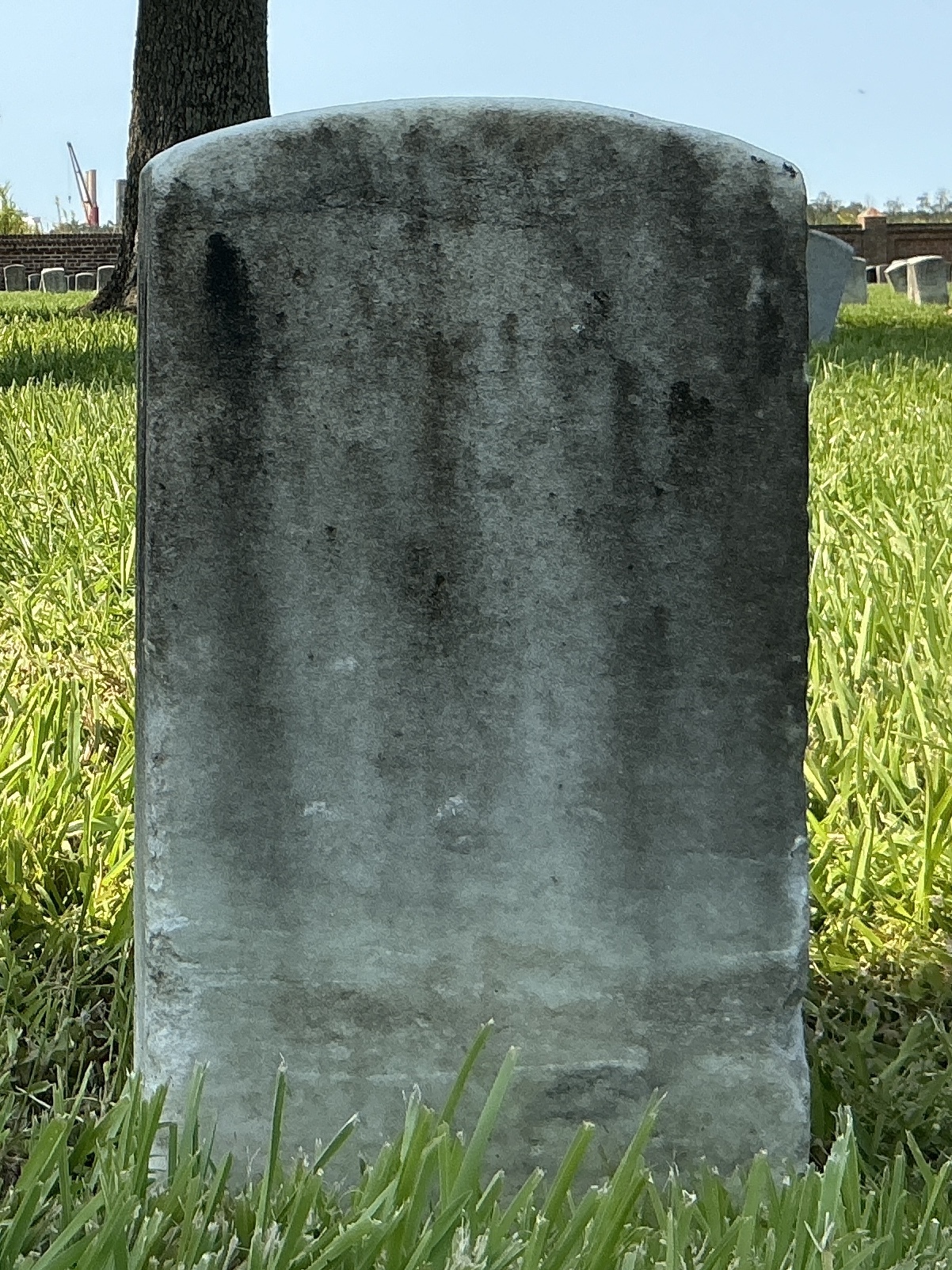 Back of historic upright marble headstone with recessed shield with recessed lettering face.