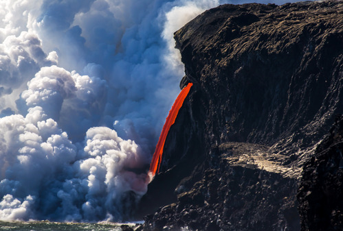 A stream of lava entering the ocean from cliffs