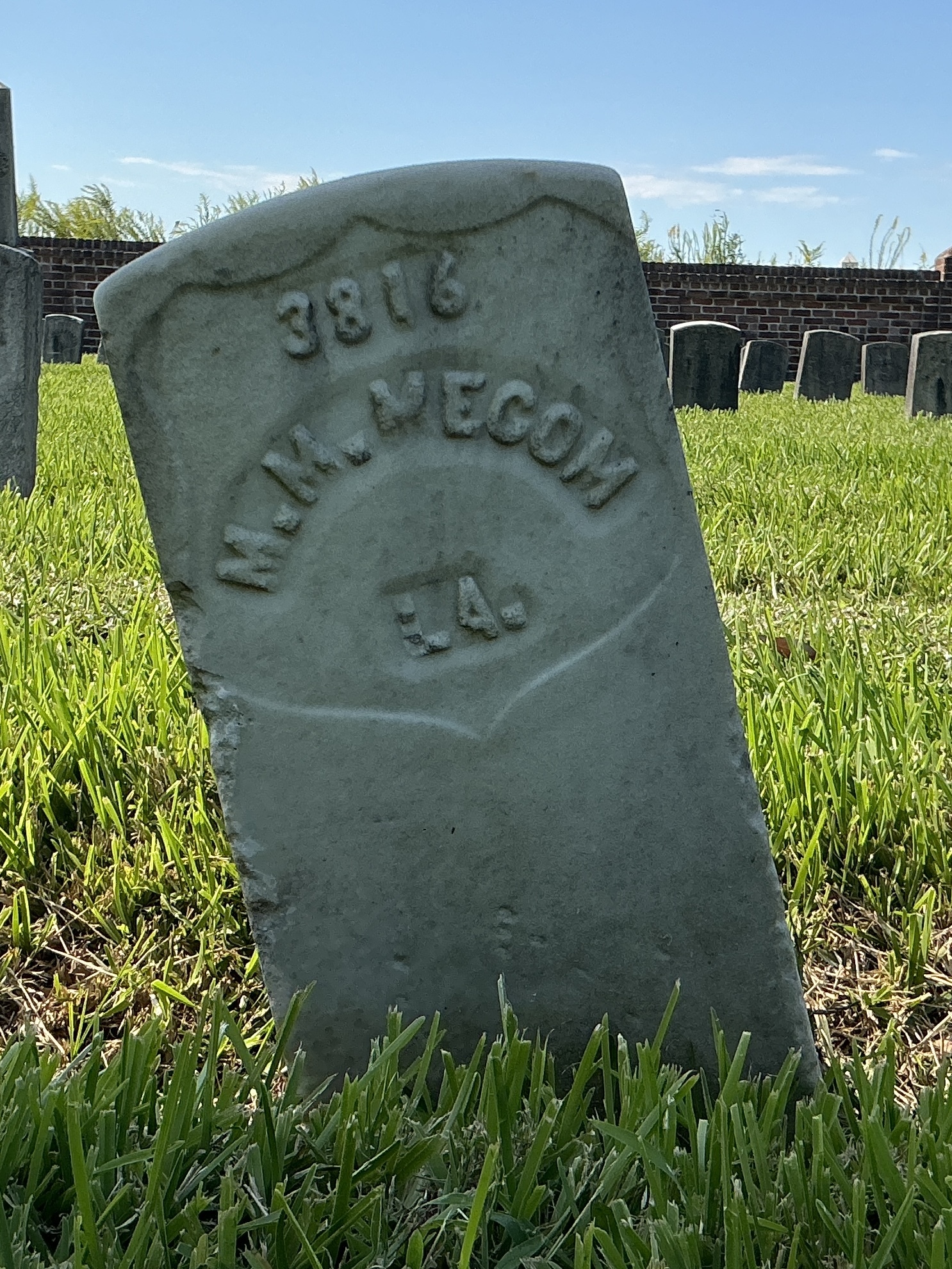 Front of historic upright marble headstone with recessed shield with recessed lettering face.
