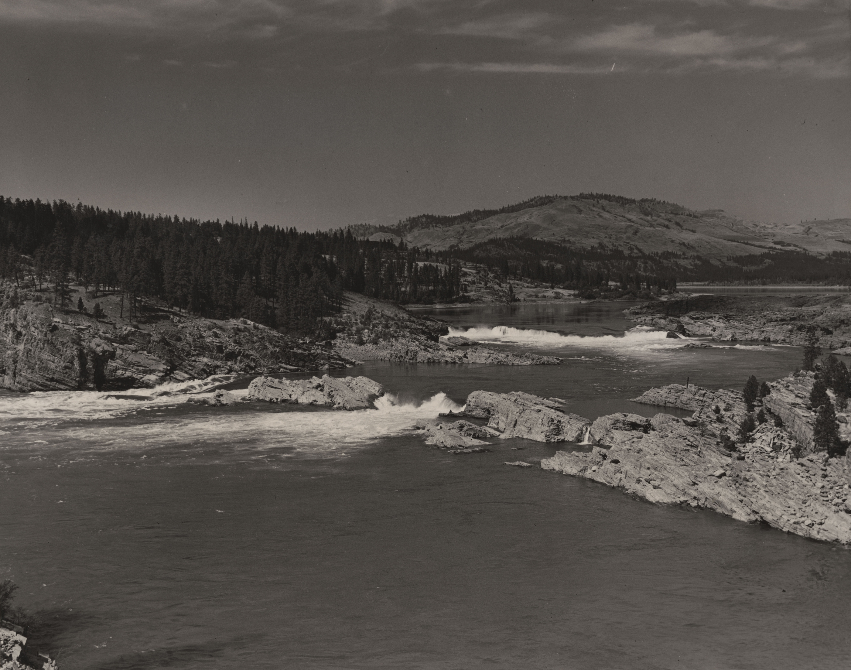 Black and white photograph of rocky rapids along a river