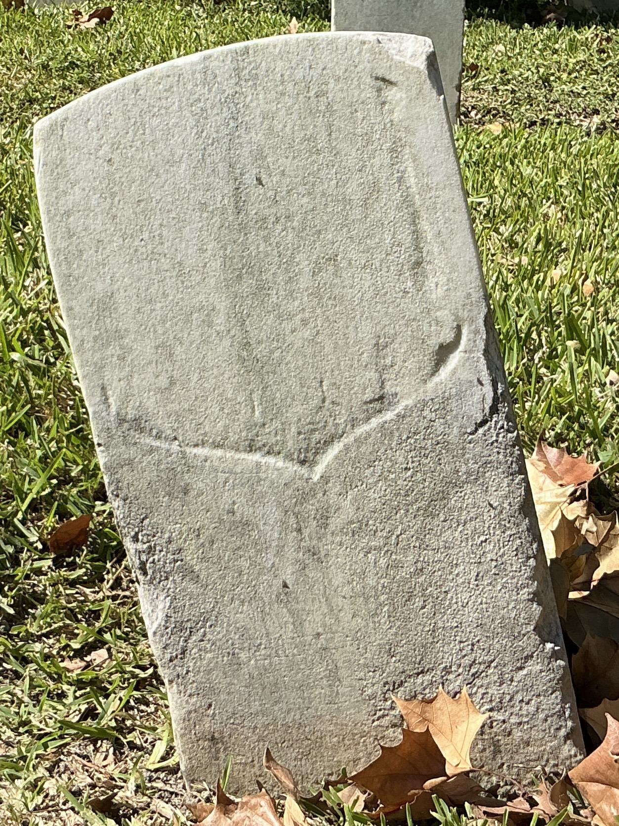 Back of historic upright marble headstone with recessed shield face.