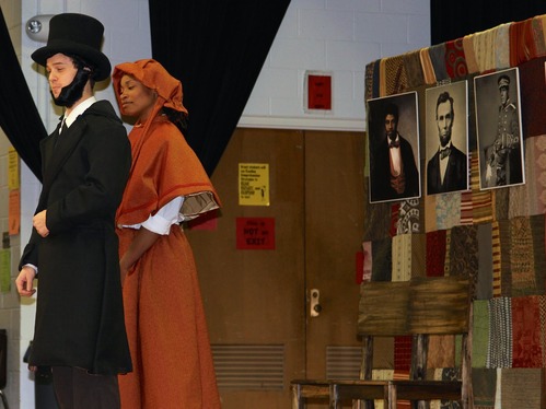 A male actor as Abraham Lincoln and female actor with red dress and bonnet.   