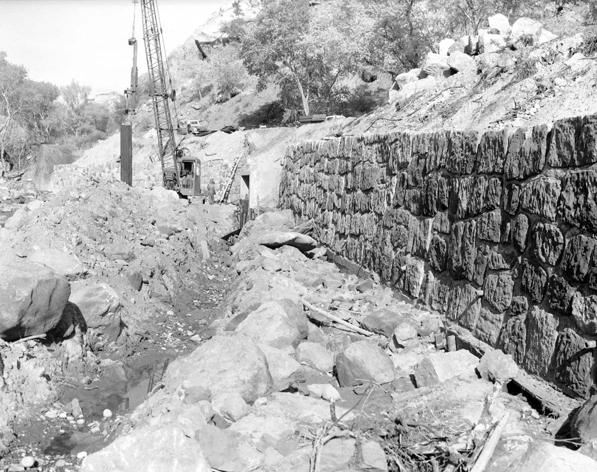 Repair of river revetment and flood damage by use of piling and restoration of rock wall.