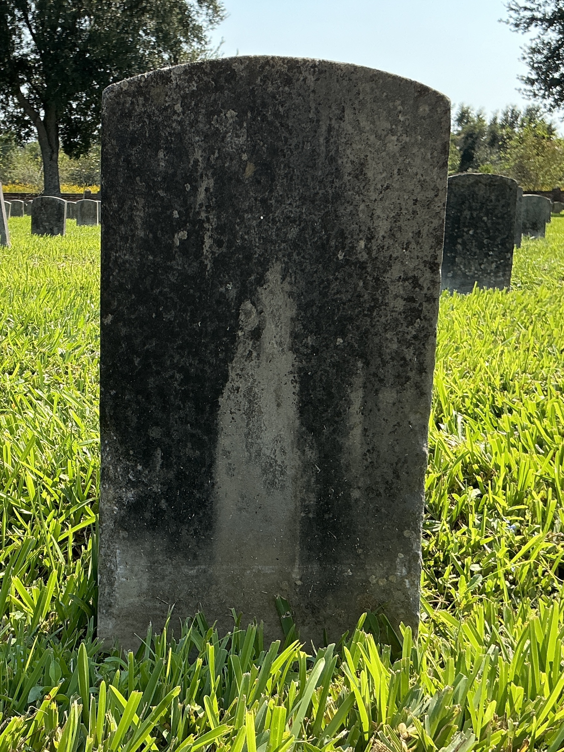 Back of historic upright marble headstone with recessed shield face.