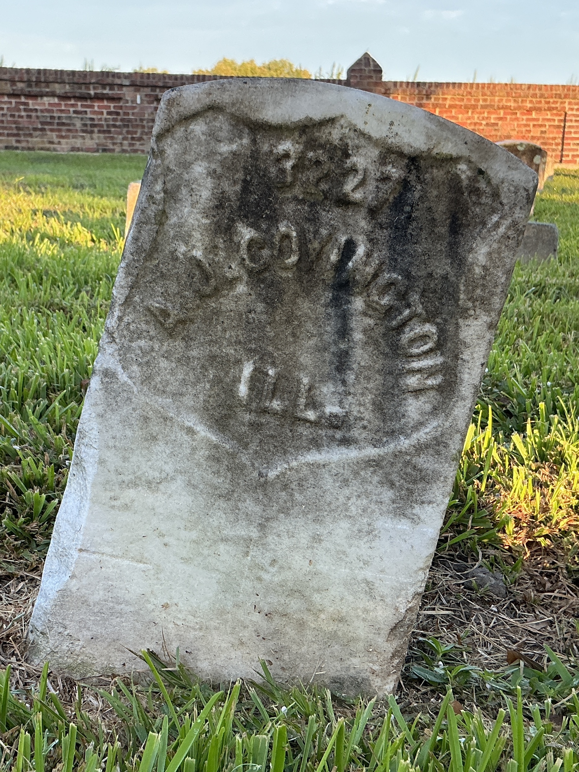 Front of historic upright marble headstone with recessed shield face.