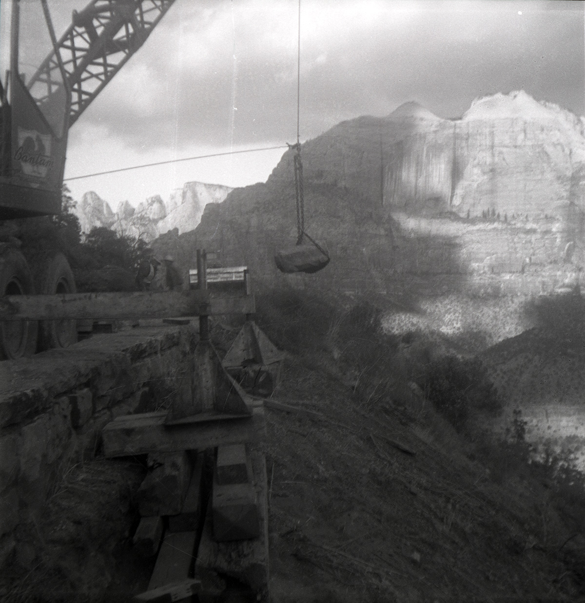 Crane lowers rock during rebuilding of rock retaining wall alongside road at the tunnel.