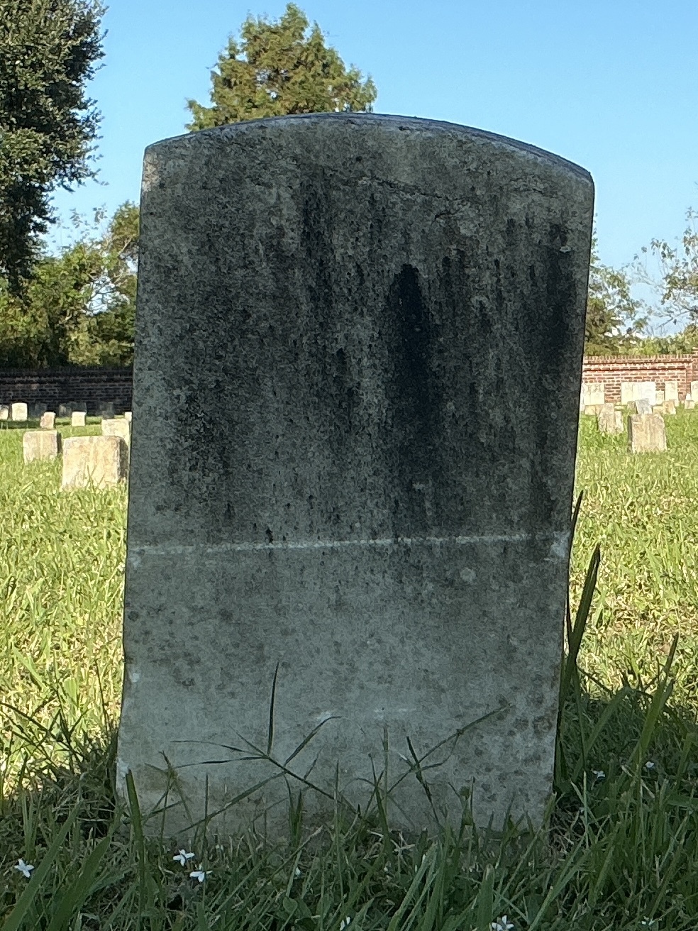 Back of historic upright marble headstone with recessed shield face.