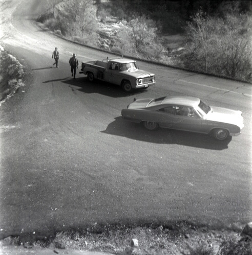 Vehicles on road with people walking during east side road repair and turn out construction.