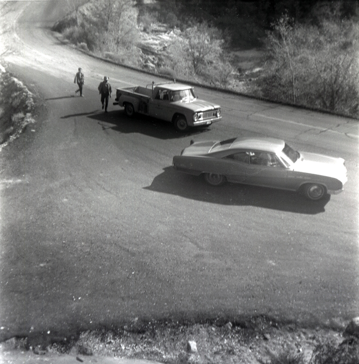 Vehicles on road with people walking during east side road repair and turn out construction.