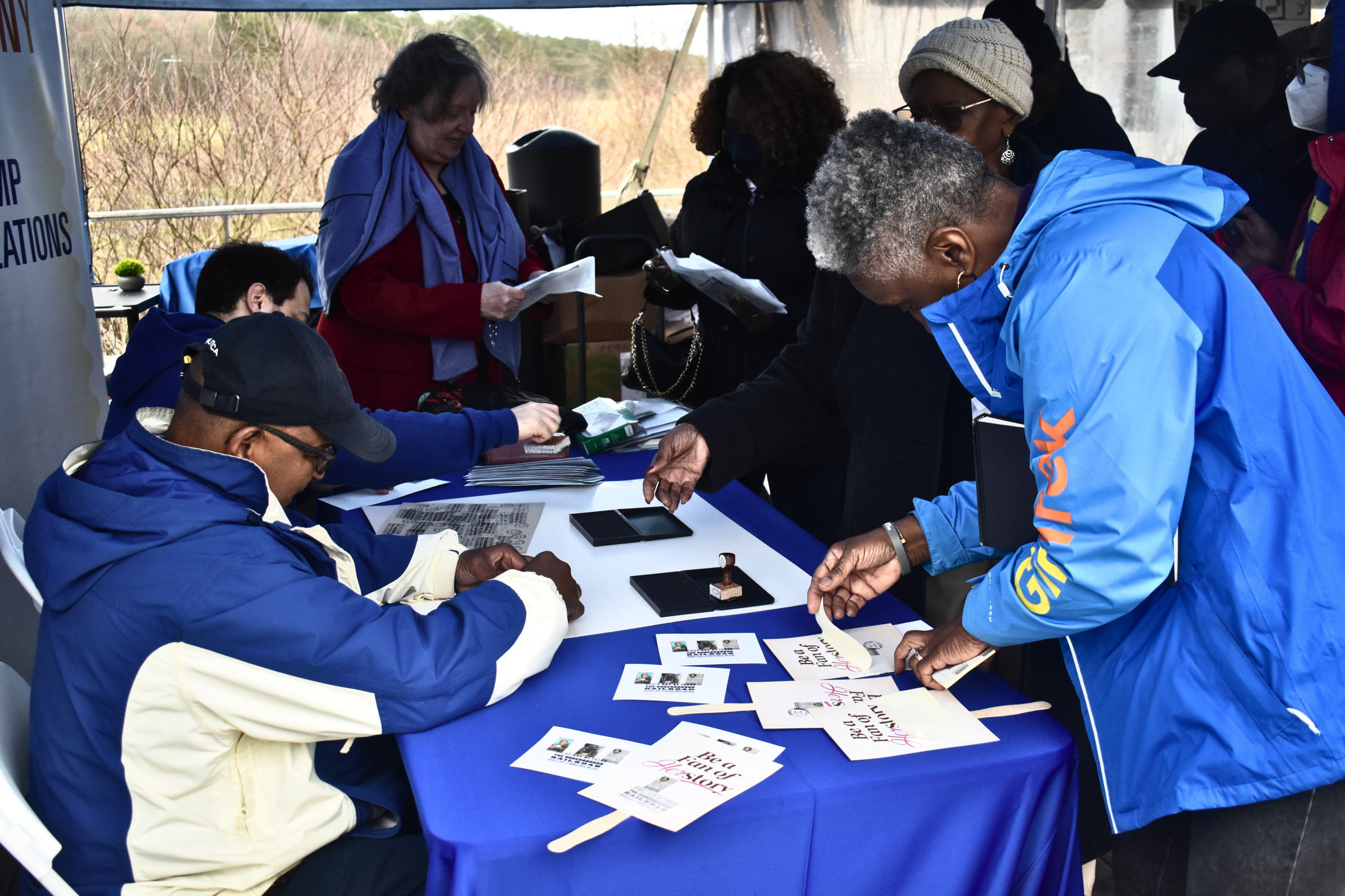 A group of people crowd around a table to get their souvenirs stamped.