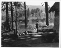 Ranger Standing outside Manzanita Lake Entrance Station. Administrative Collections: Album 5 (Emergency Conservation Works) -Manzanita Lake Entrance Station with Manzanita Lake in background.