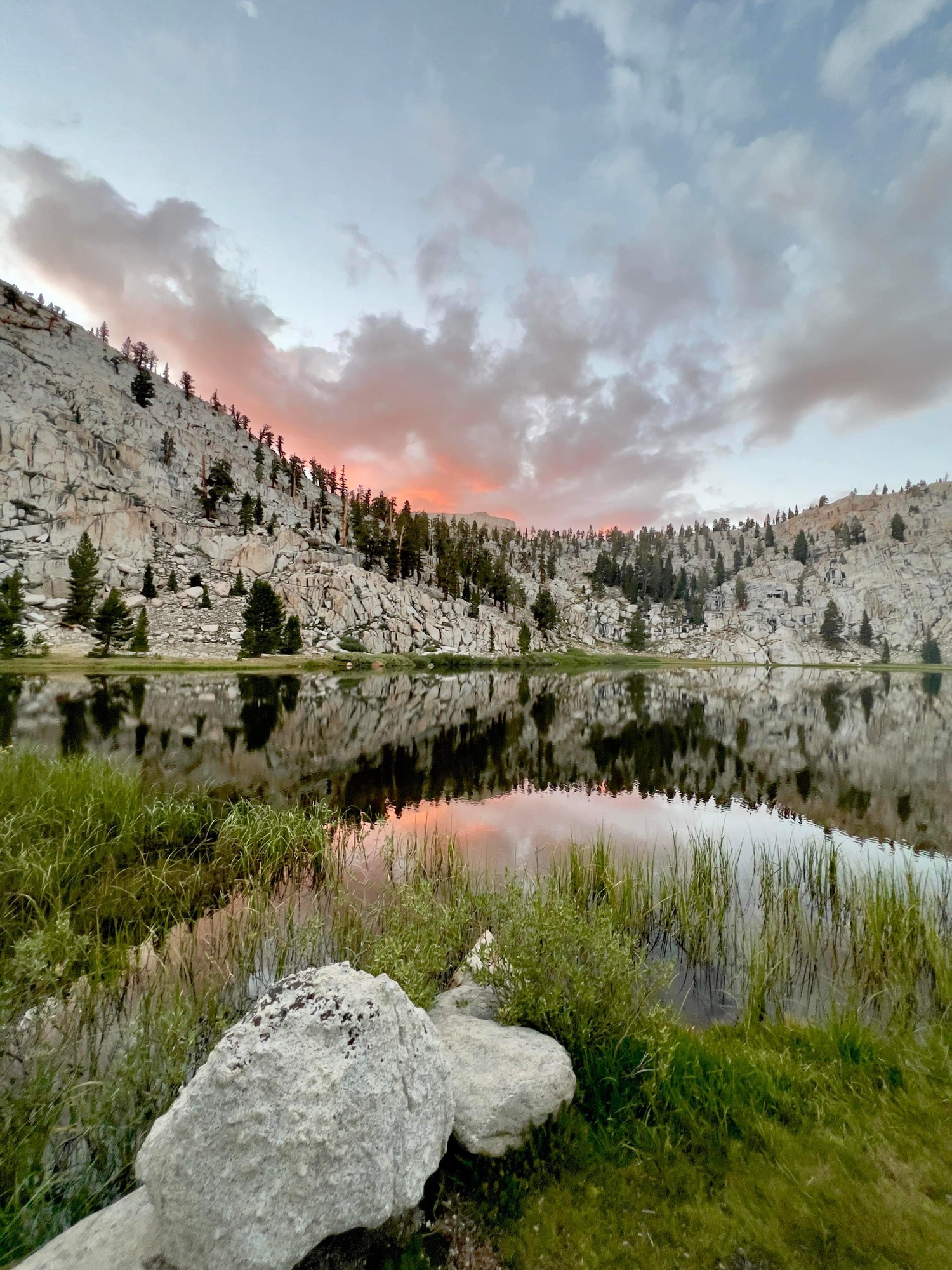 a granite mountain vista and sunset sky reflected in a lake