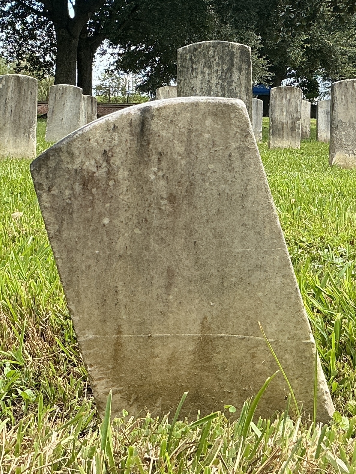 Back of historic upright marble headstone with recessed shield face.