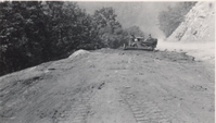 Bulldozer spreading topsoil on day lighted section