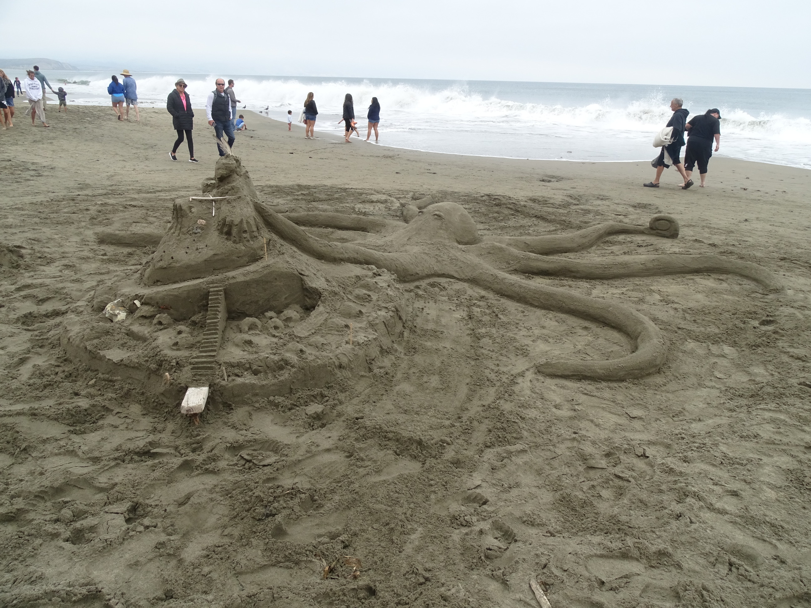 A sand sculpture of an octopus or a kraken attacking a castle.