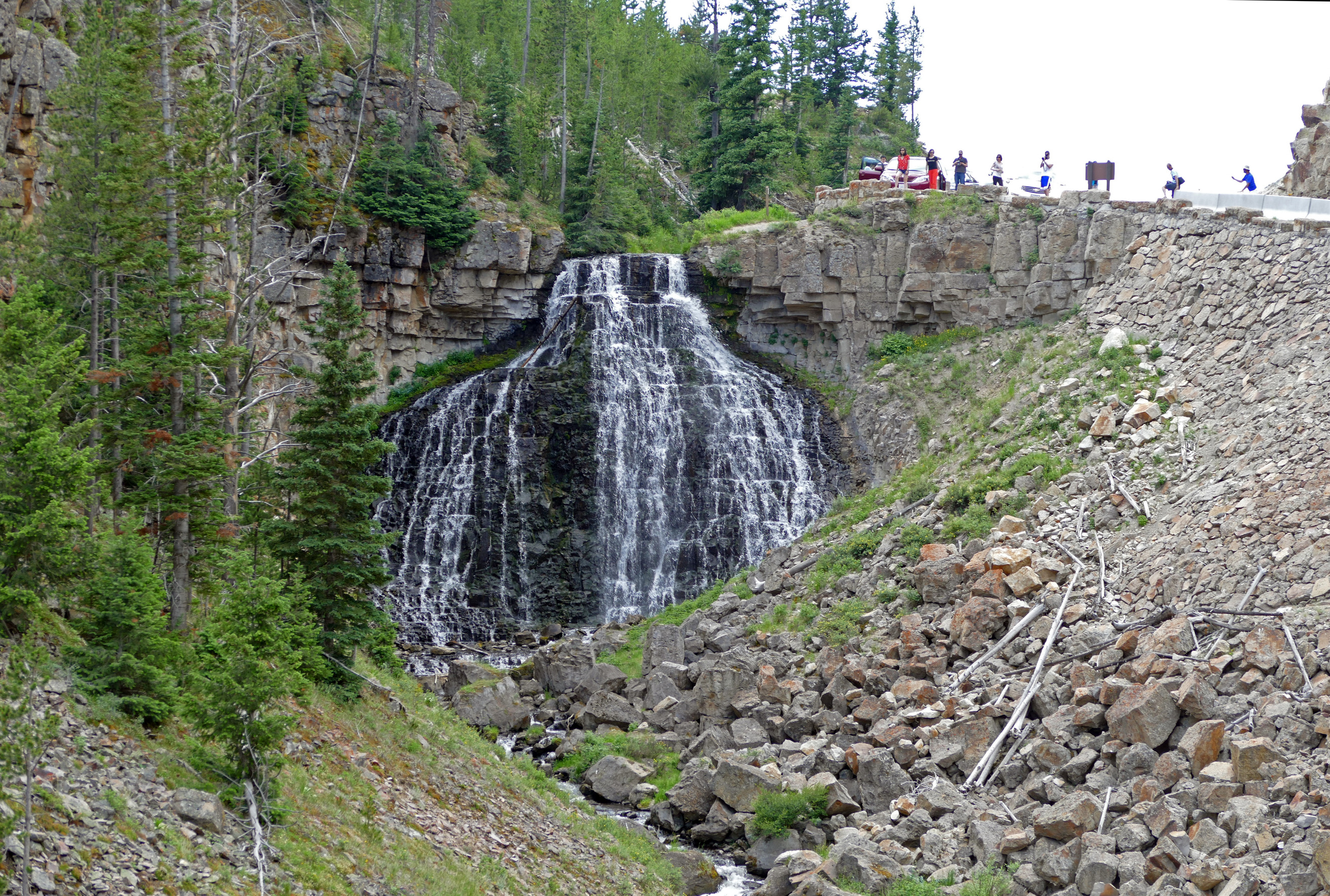 People stand at the top of a waterfall with cameras in their hands.