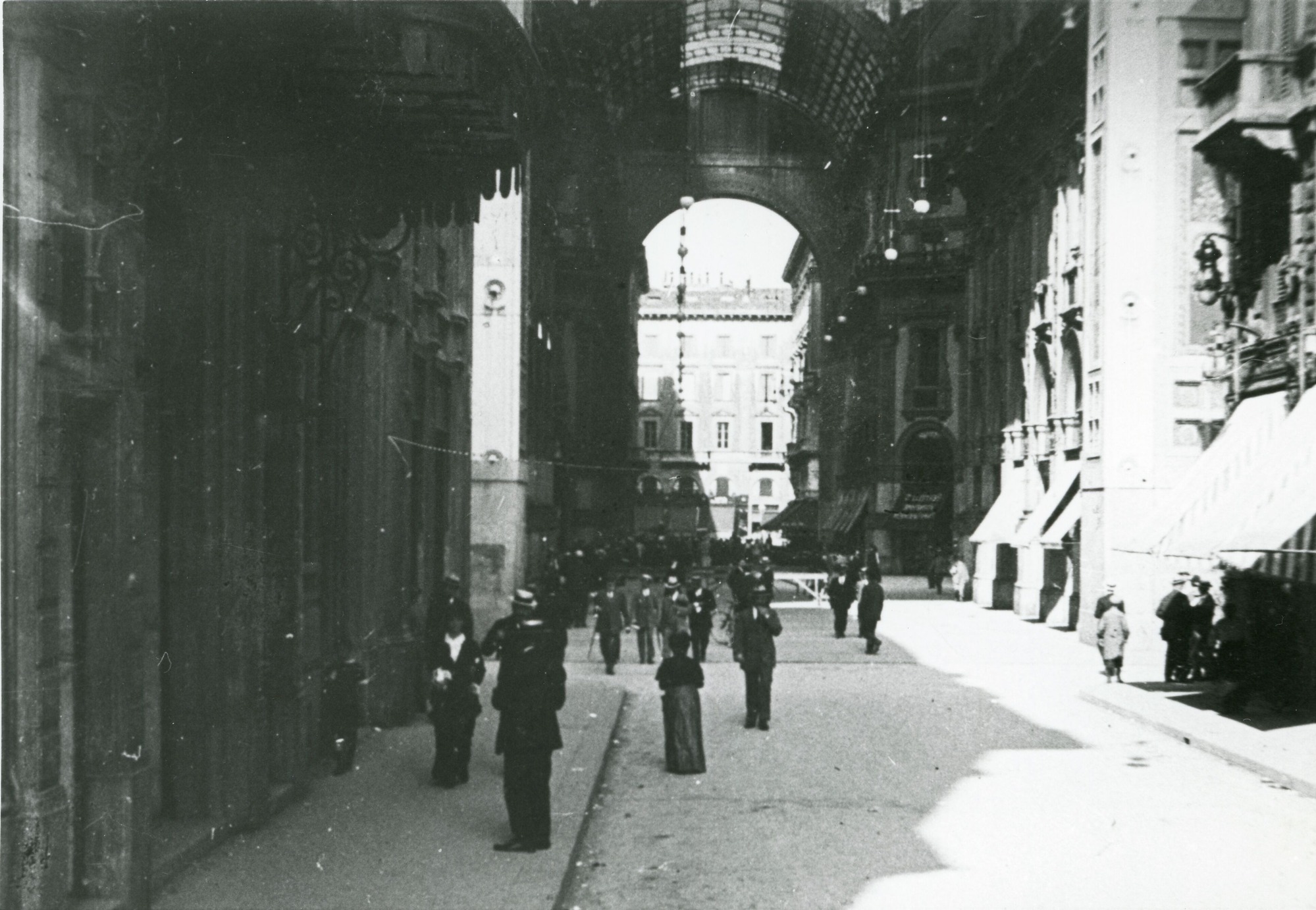 People walking and standing on a paved European city street.