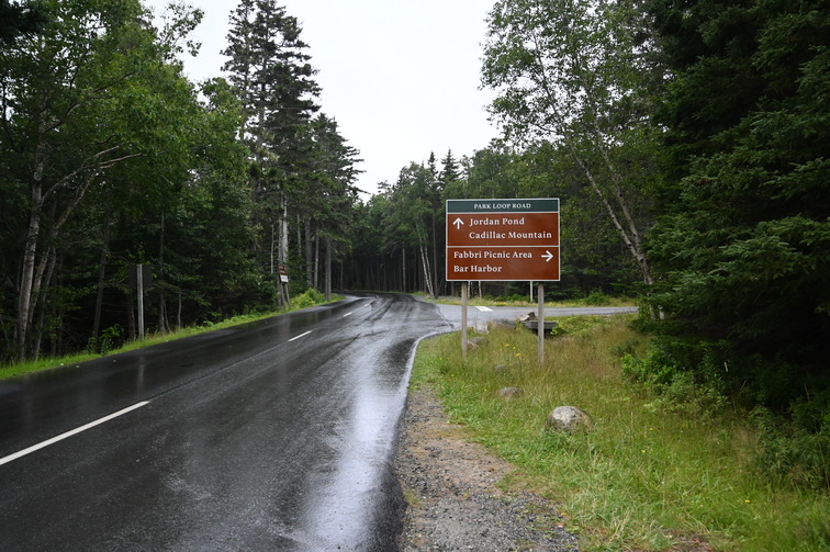 Roadway with large brown sign pointing right to Fabbri Picnic Area and Bar Harbor