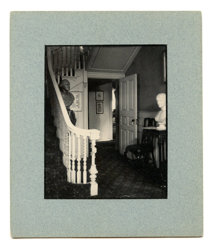 Hallway with two busts and an open door.