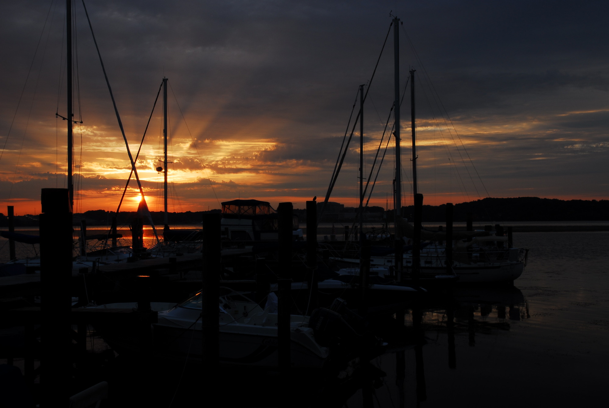 The sun sets behind a pier with boats