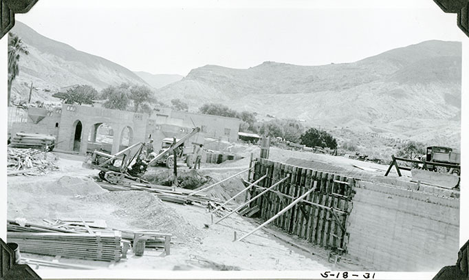This is an historic black and white photograph from the Scotty's Castle Historic Photograph Collection, Death Valley National Park of Scotty's Castle Swimming Pool, west end looking east. Men working with power shovel and dump truck. Shows forming and hollow tiles. May 18, 1931. Photographed by Mat Roy Thompson.