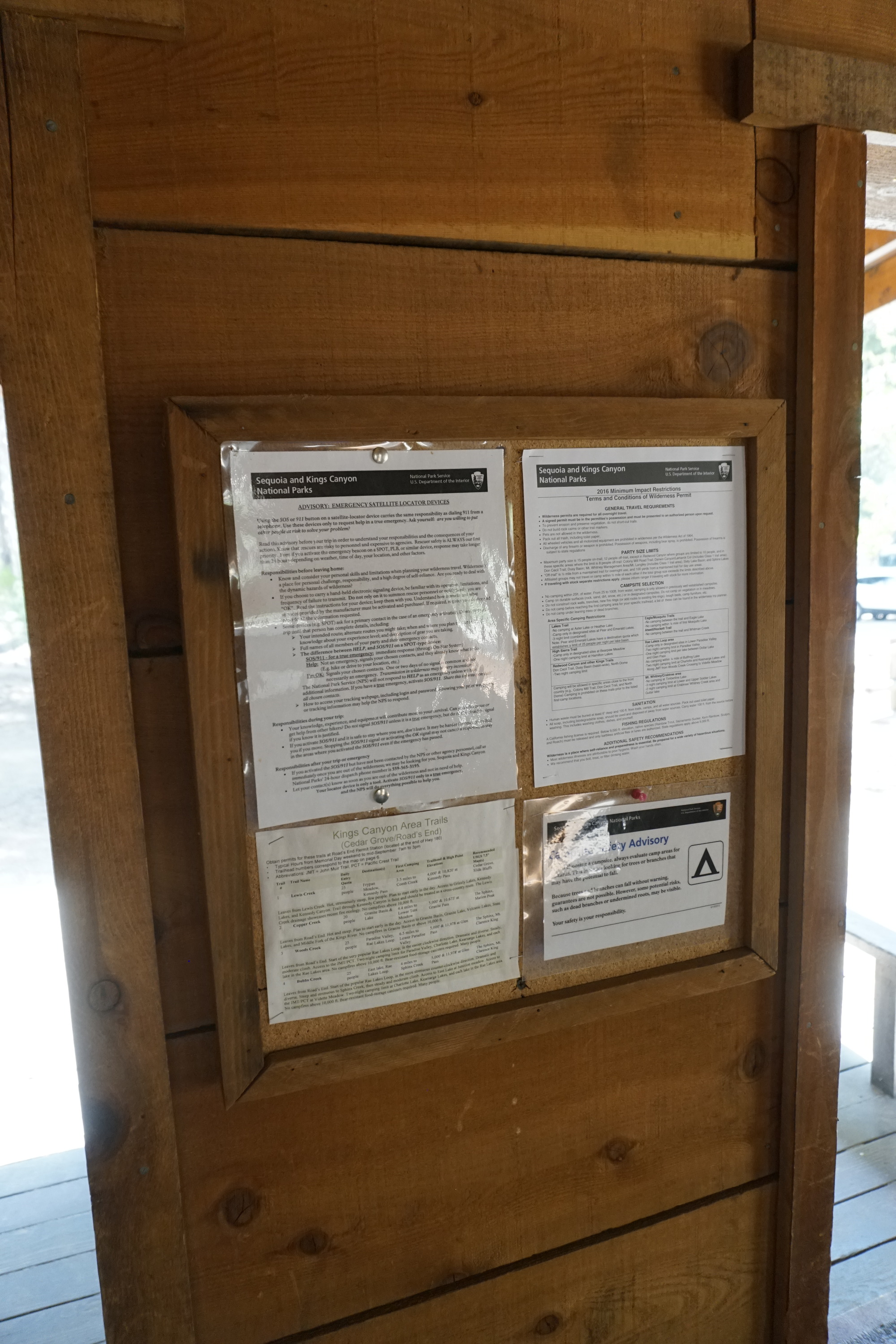 Four Laminated pieces of paper are tacked to a corkboard bulletin board. 