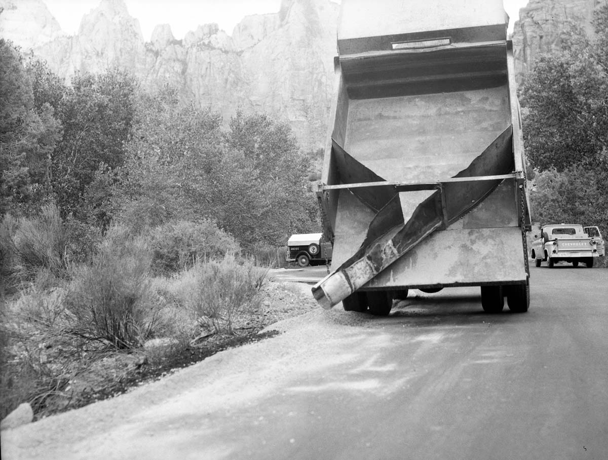 Road maintenance - truck bed and chute of gravel spreader dump truck, truck bed fully raised. Towers of the Virgin in background.