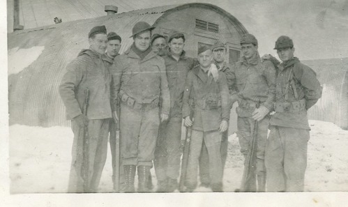 Group of men standing in front of quonset hut in the snow