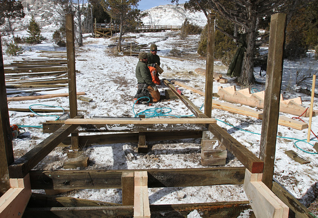 Two men on ground building the framework of a boardwalk