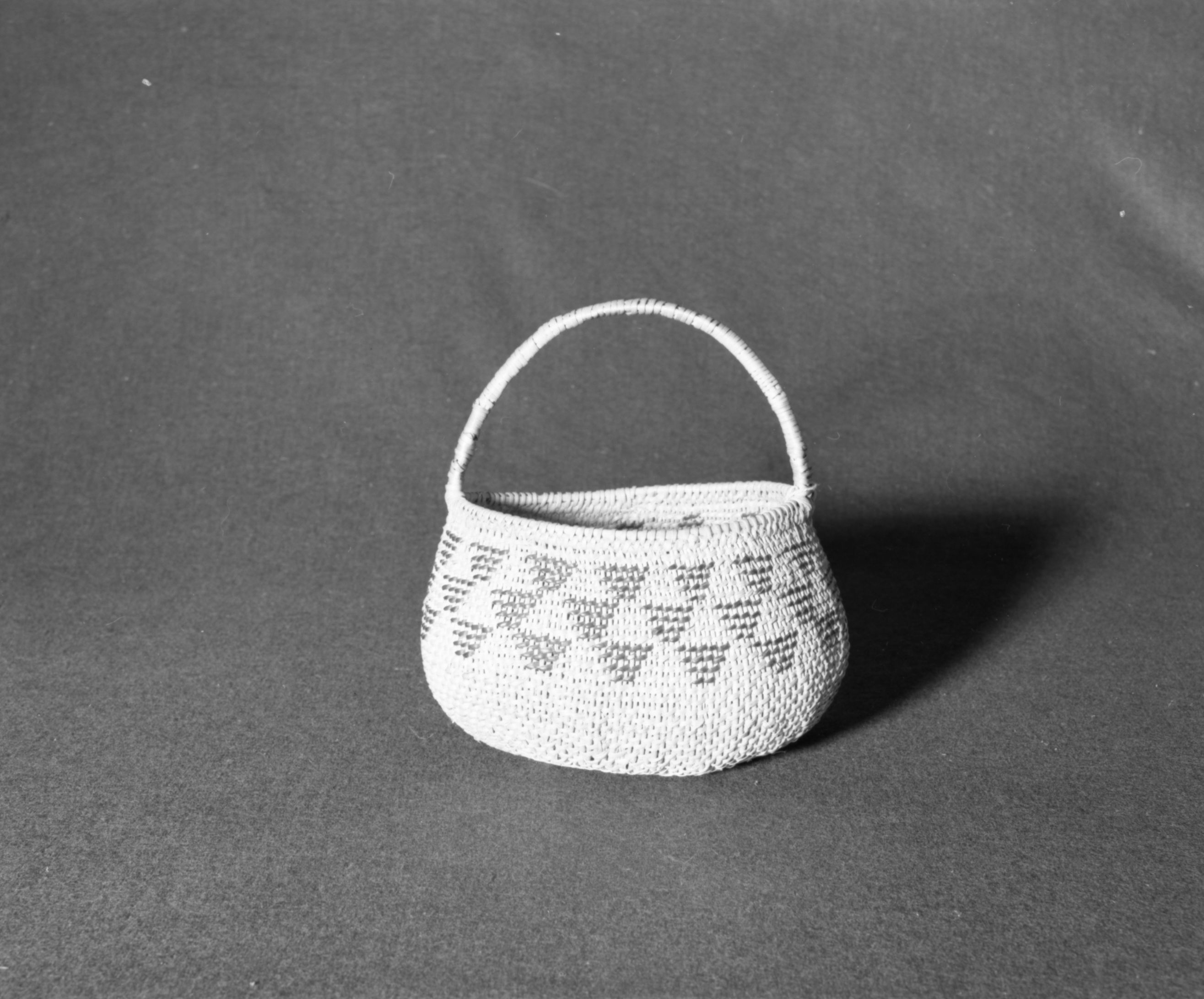 Marie Rozier Collection, Catalog No. 24. Object: Miwok handled basket. Dimensions: 8 1/2 x 10 x 5 1/2". Materials: split redbud, split bull pine or ceanothus. Technology: diagonal twined. Collection History: Alice Reade collection. Photographed by Michael Dixon, December 1982. Catalogued by Craig Bates and Barbara Beroza. Yosemite Collections, National Park Service.