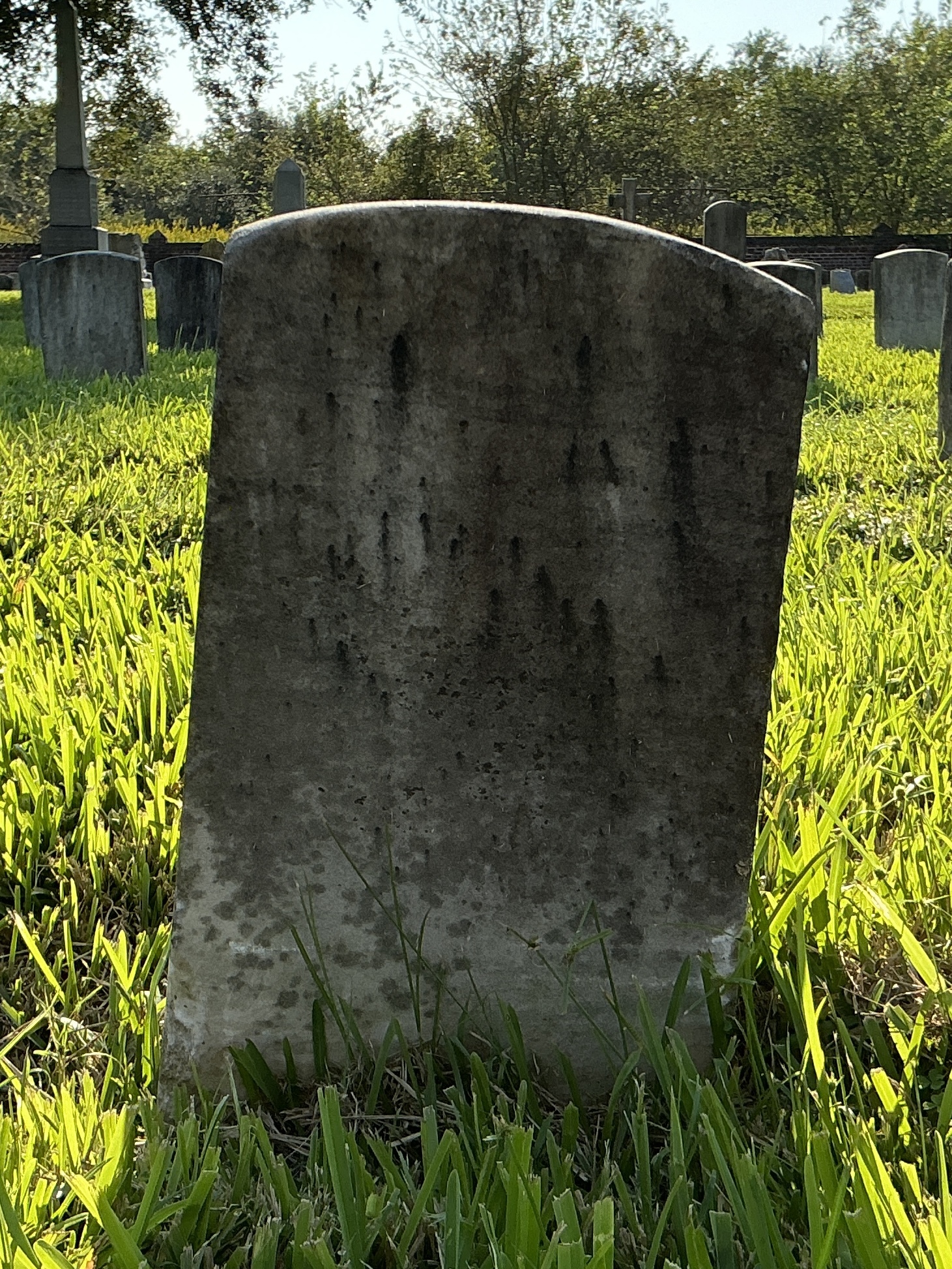 Back of historic upright marble headstone with recessed shield face.
