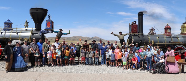 Visitors and Staff gather around the front of two historic locomotives