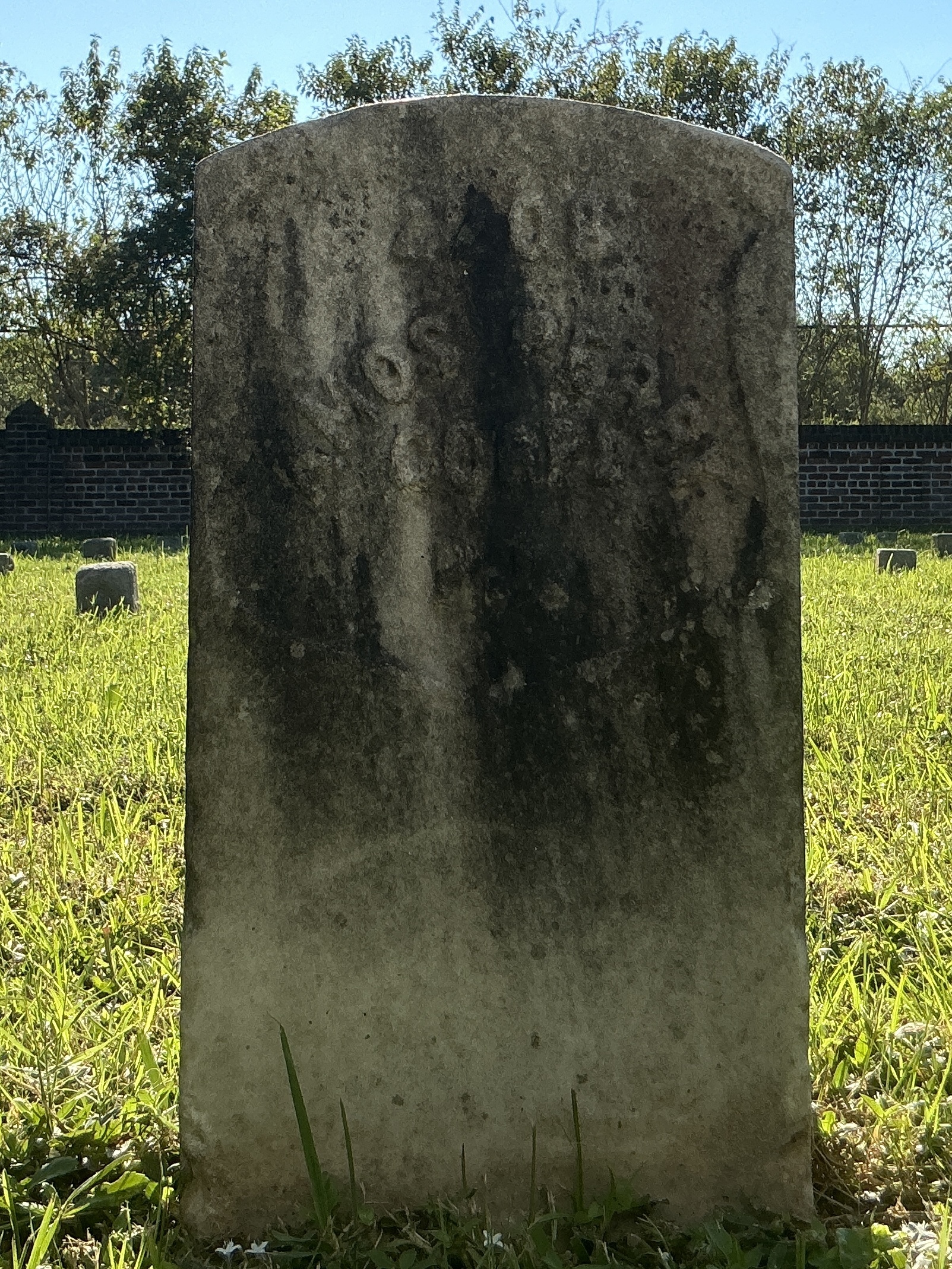 Front of historic upright marble headstone with recessed shield face.