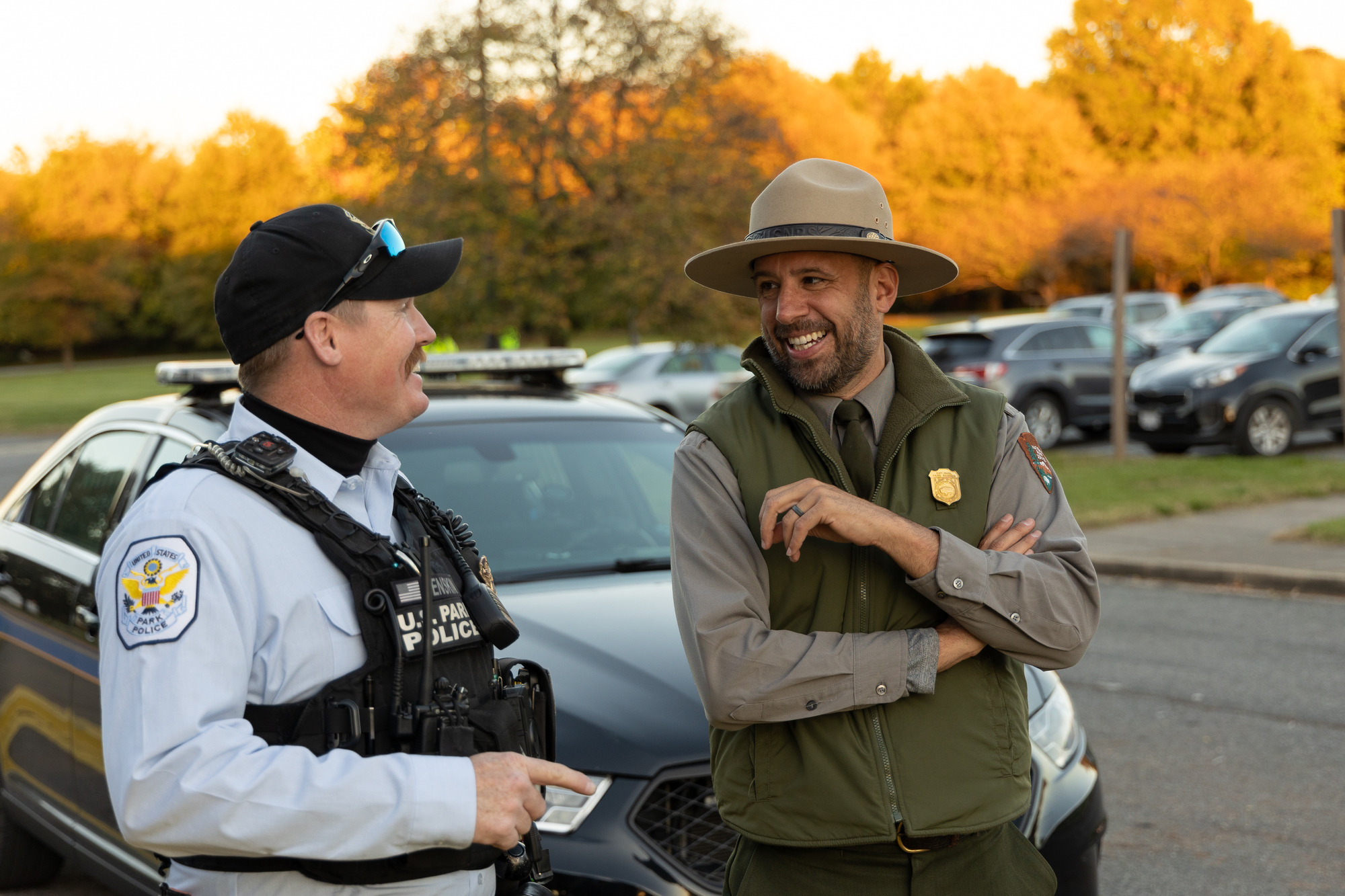 A park ranger and a police officer stand smiling next to each other.