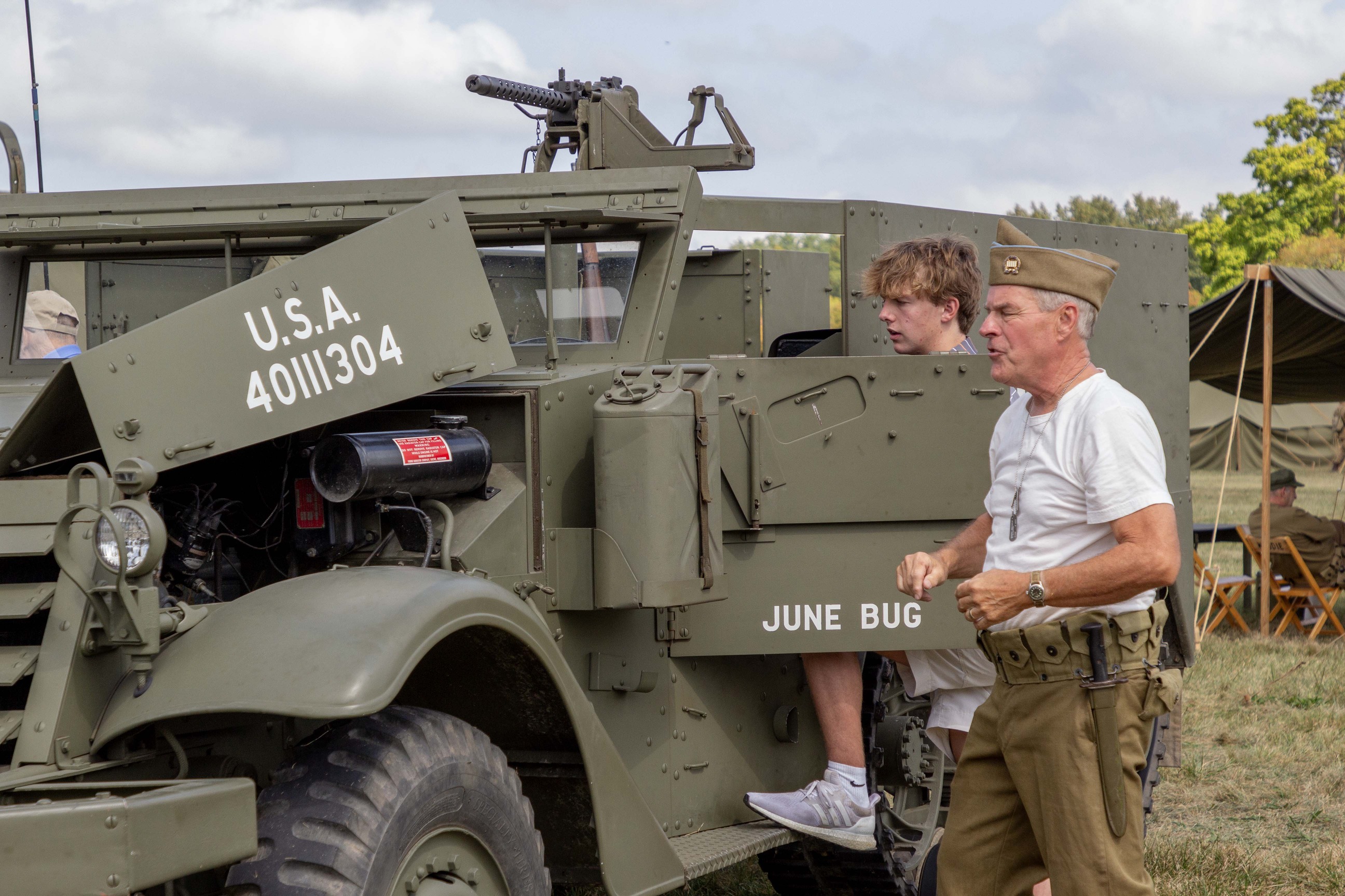 Several historic vehicles. Visitors look at them and talk to living history volunteers. 