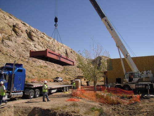Railroad car being unloaded from trailer before placement on the bridge abutments.