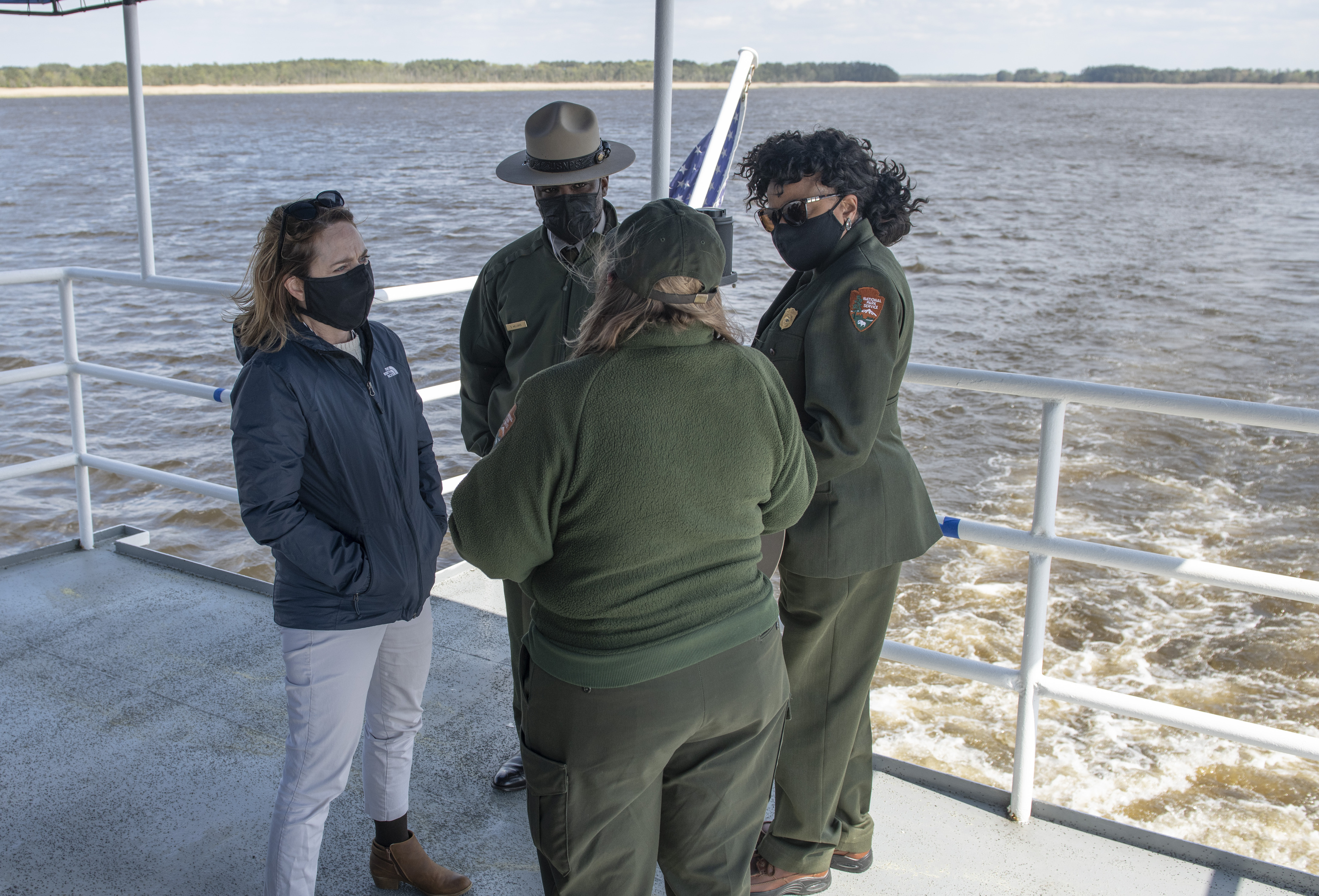Four federal officials having a conversation on the deck of a boat.