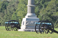 Two Cannon in a sunny field with a stone monument in between them