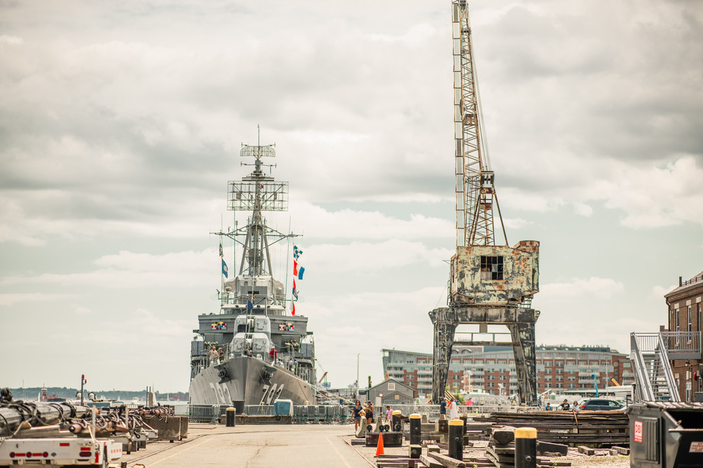 View of the USS Cassin Young with bright flags blowing in the wind and a tall crane off to the right