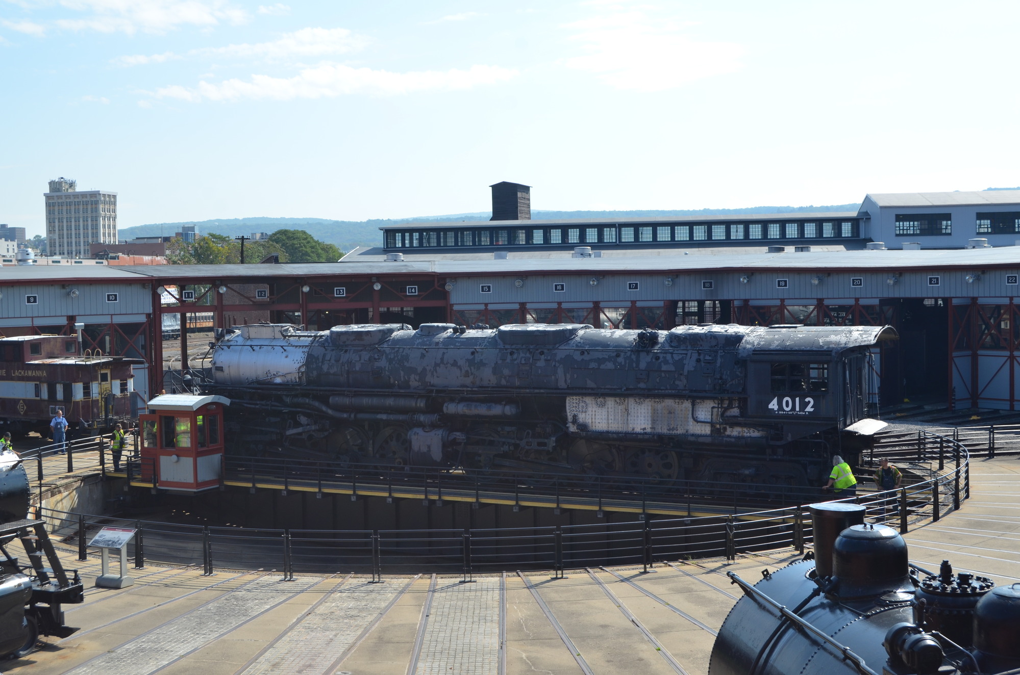 Elevated exterior view of a large train on a turntable with 3 people looking on.