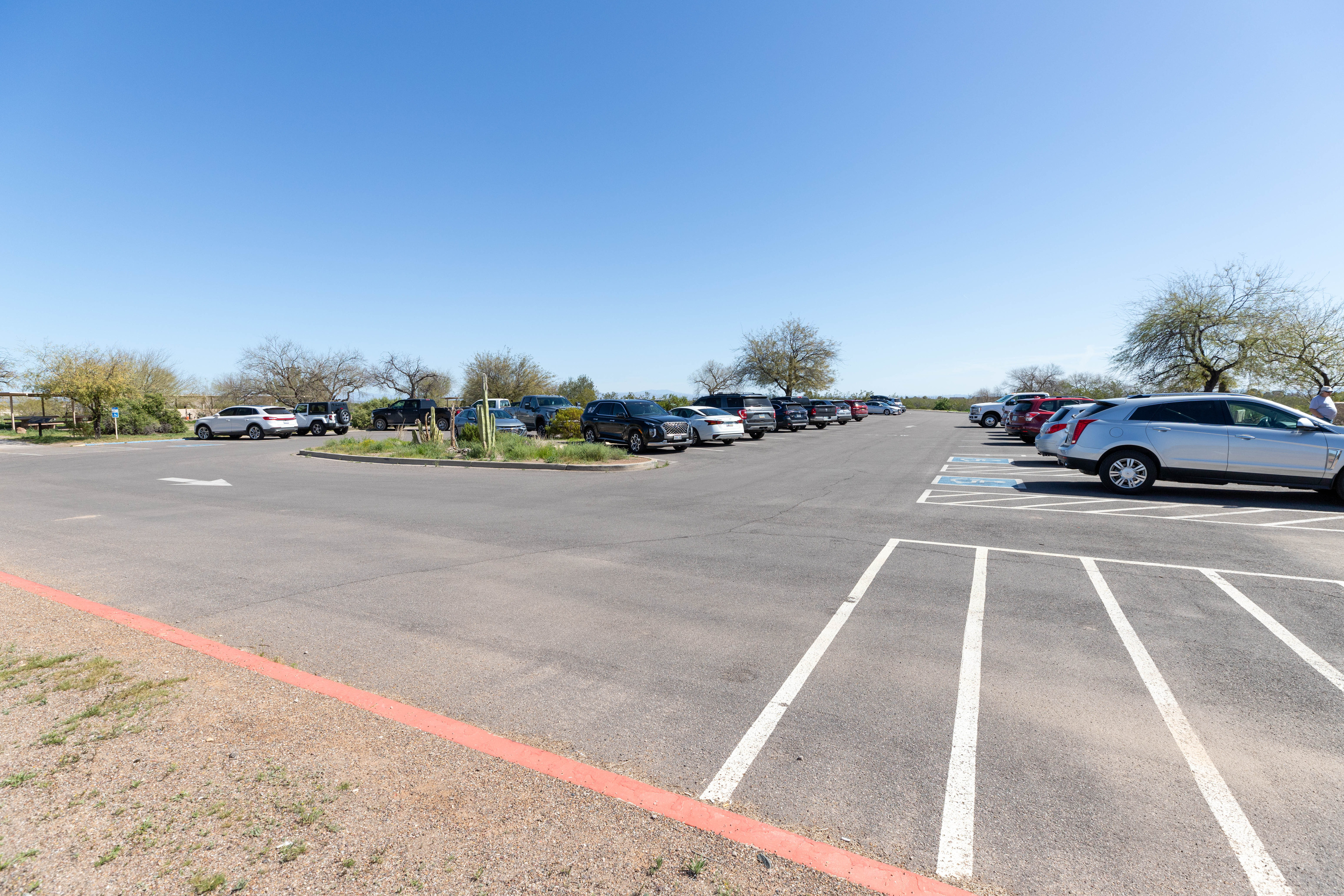 A large paved parking lot with many parked cars. 