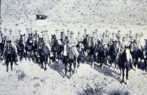More than twenty mounted cavalrymen and their horses pose for a photo from the 1910s.