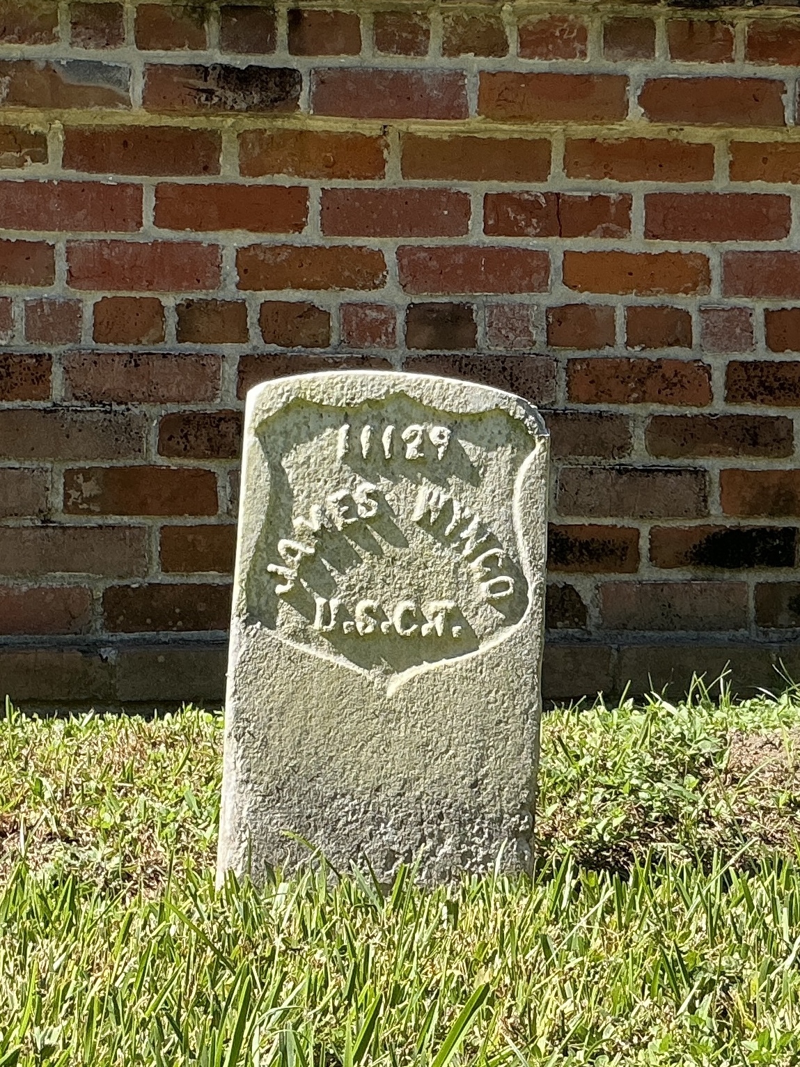 Front of historic upright marble headstone with recessed shield face.